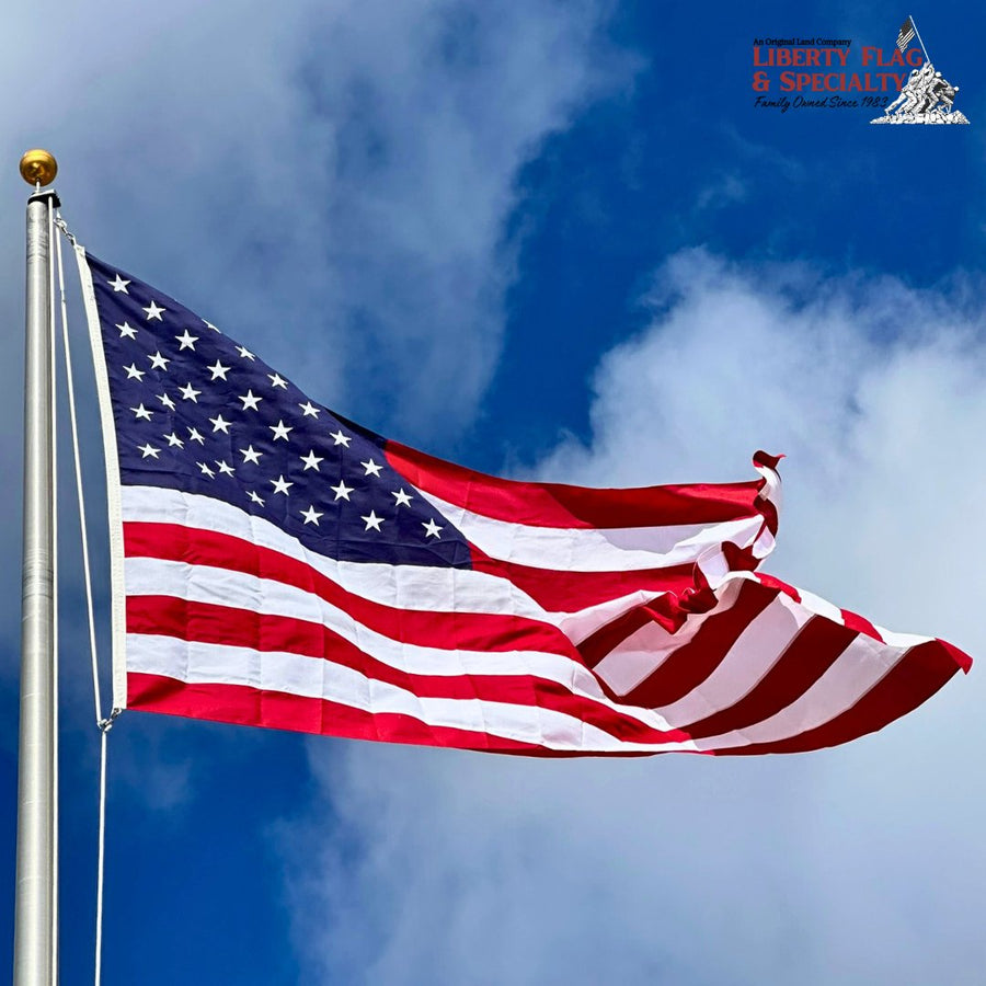 Polyester American flag flying on an outdoor flagpole against a blue sky