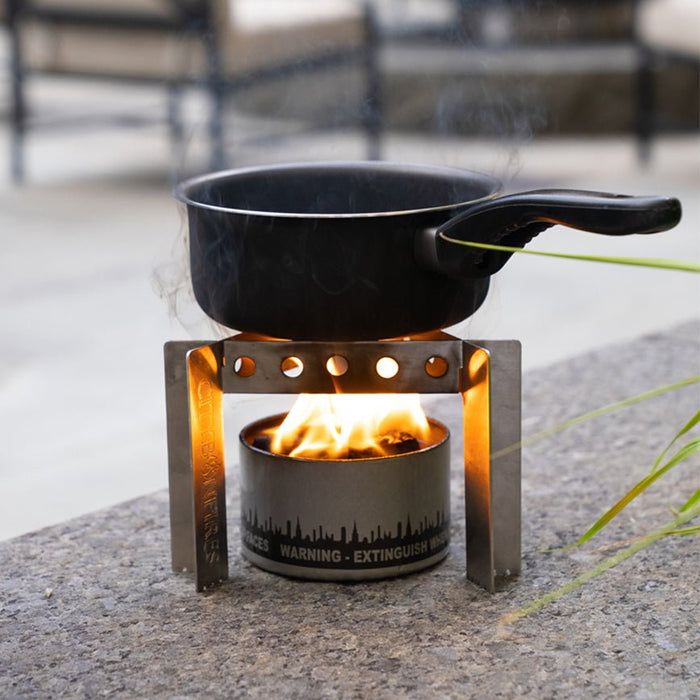 Cooking pot supported above a bonfire by the stainless steel stove