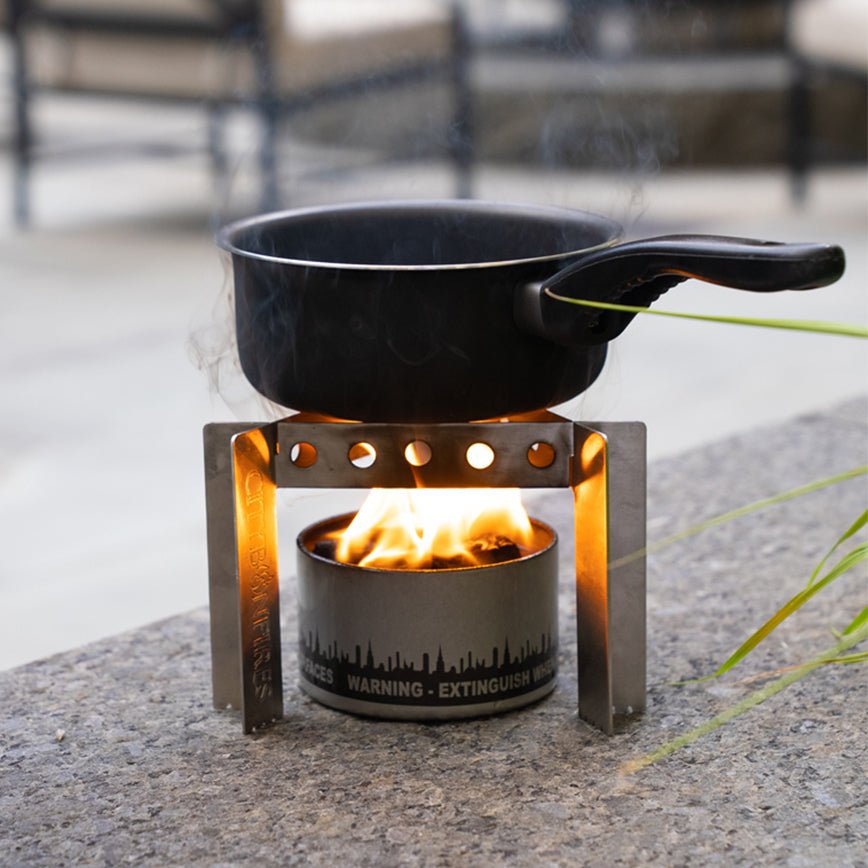Cooking pot supported above a bonfire by the stainless steel stove