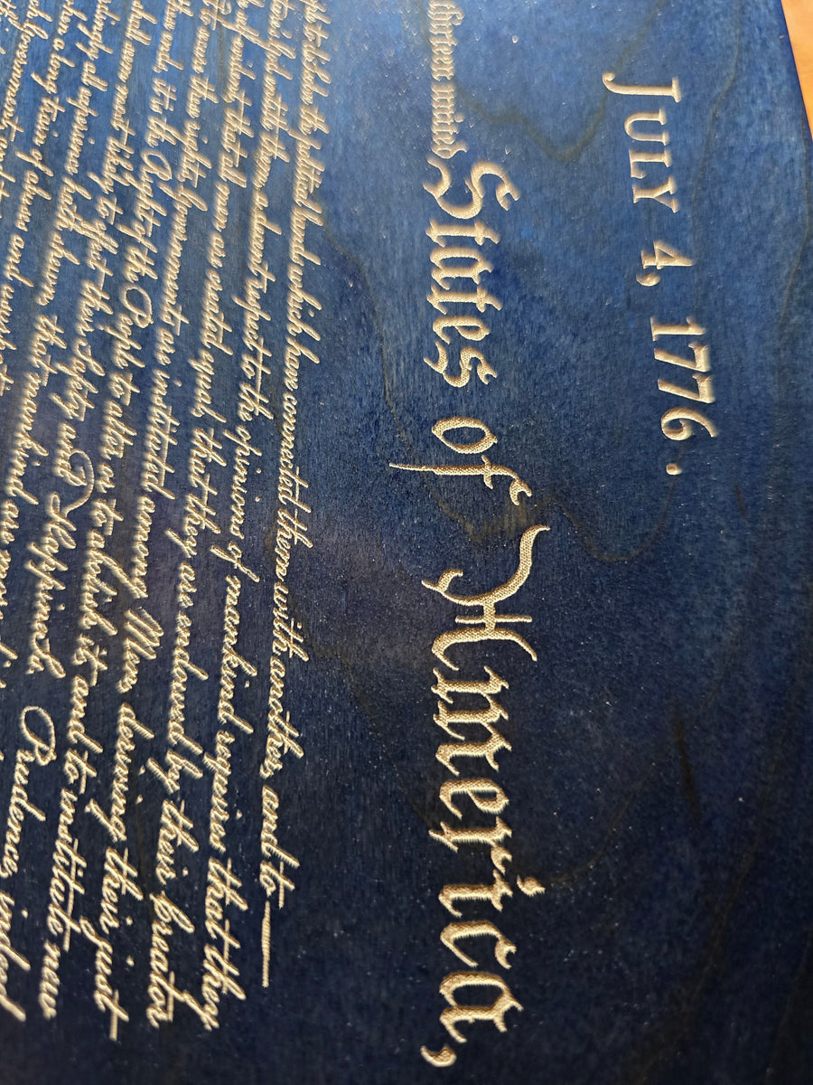 Close-up of engraved July 4 1776 heading and Declaration text on blue wooden plaque