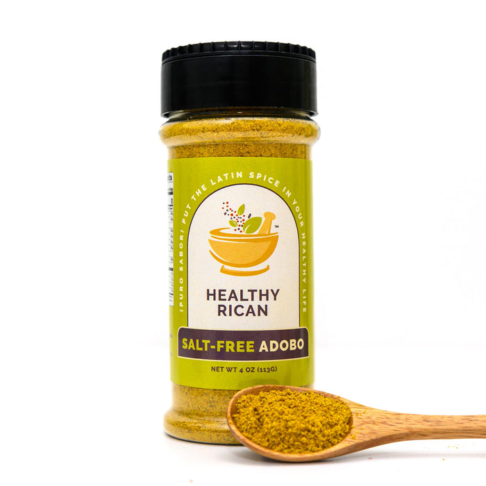 Salt-free adobo seasoning jar beside a wooden spoon of yellow spice blend