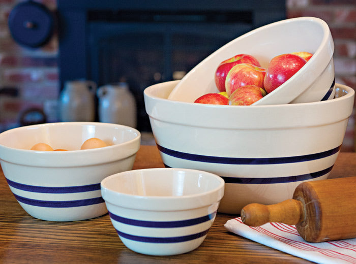 Blue-striped stoneware shoulder bowls in several sizes arranged with fruit and baking utensils