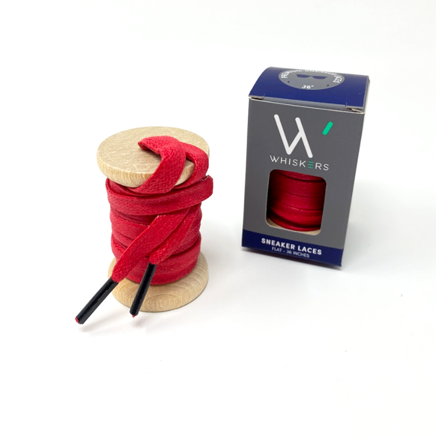 Red glazed cotton shoelaces on a wooden spool beside the retail box
