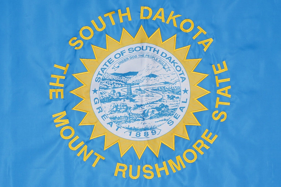 South Dakota state flag close-up with gold sunburst and Mount Rushmore State lettering