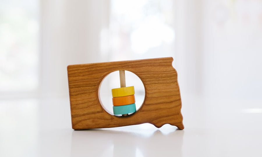South Dakota state-shaped cherry wood baby rattle with colored center disks