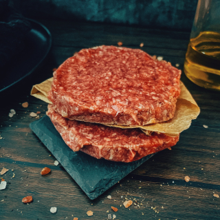 Stacked raw Wagyu burger patties on a slate board