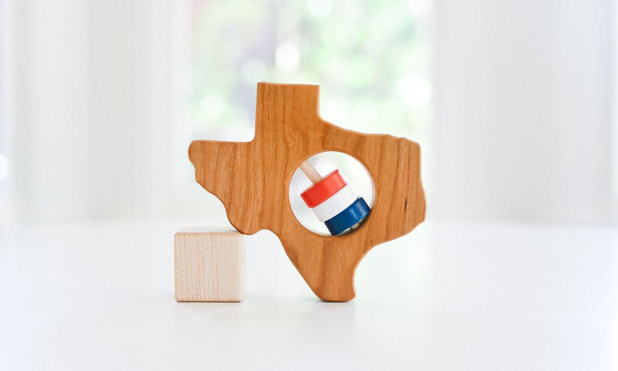 Texas state-shaped cherry wood baby rattle with colored center disks