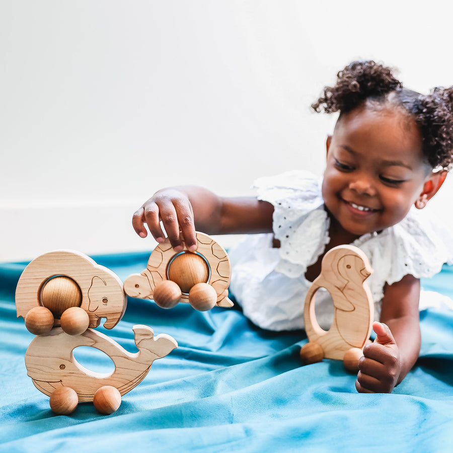 Children exploring wooden animal push toys with spherical wheels