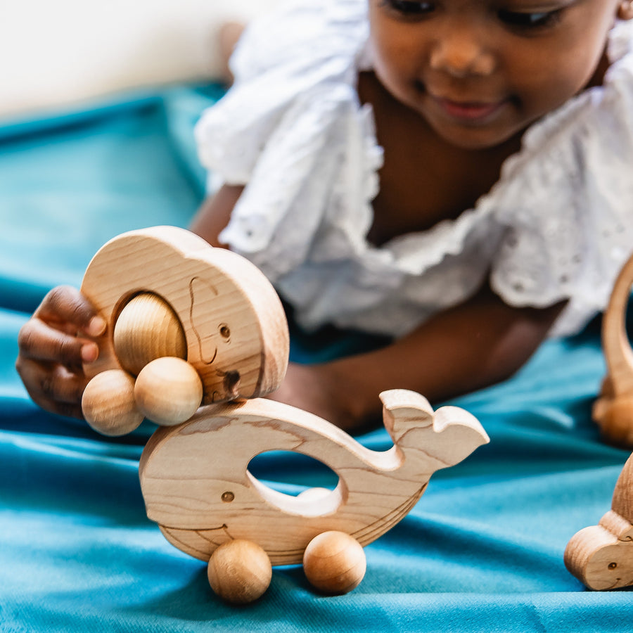 Children exploring wooden animal push toys with spherical wheels