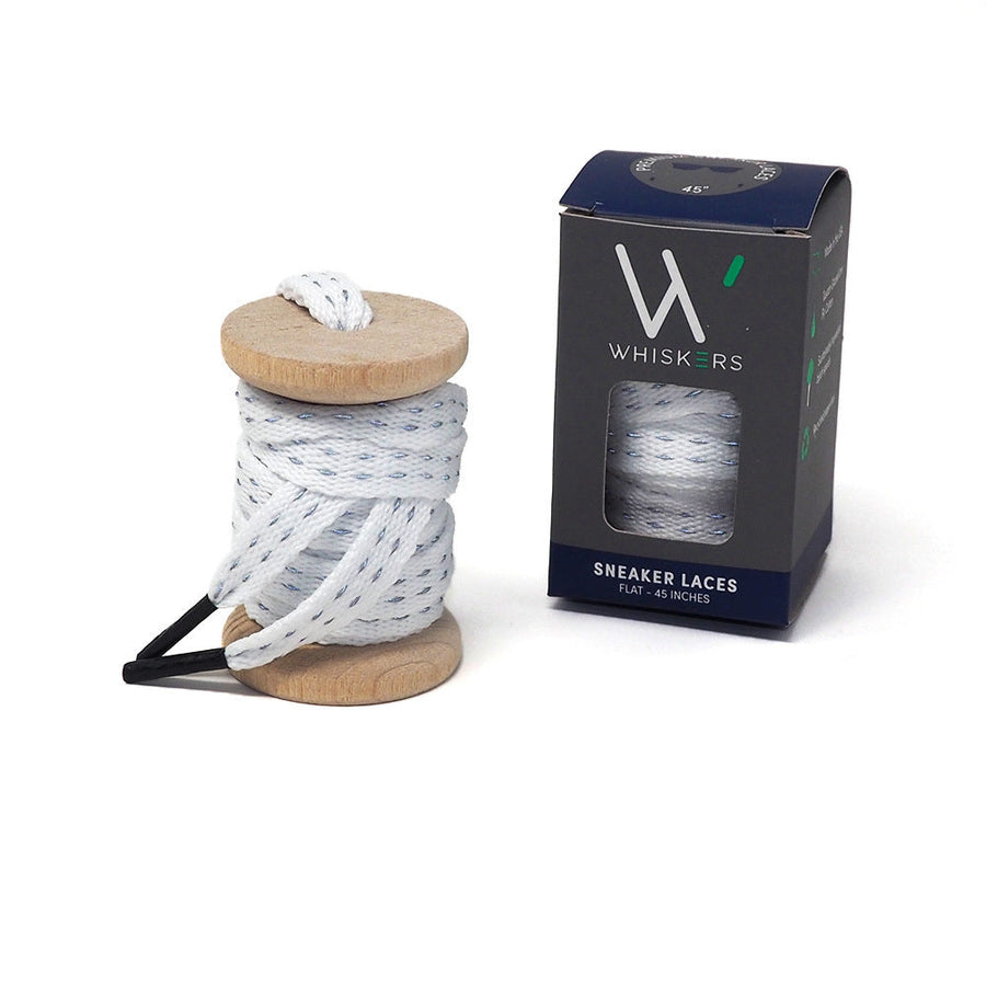 White reflective shoelaces on a wooden spool beside the retail box
