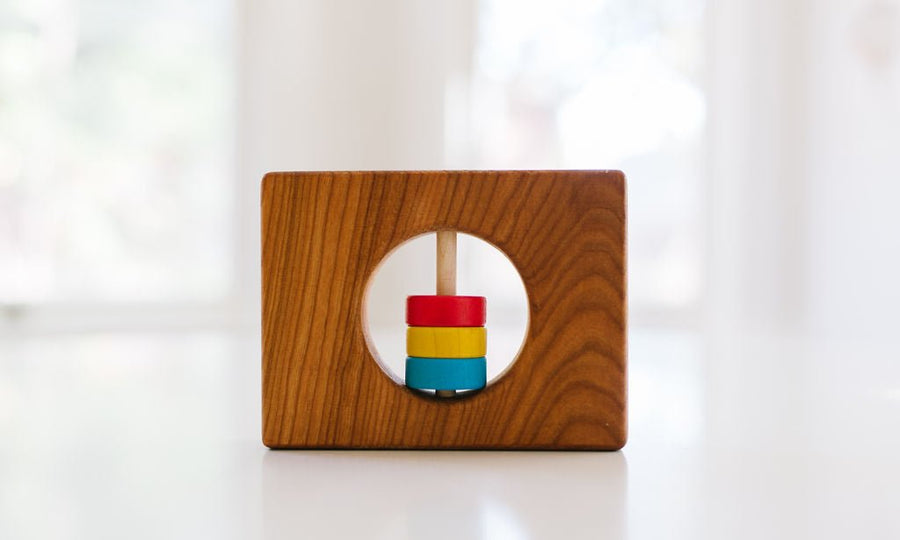 Wyoming state-shaped cherry wood baby rattle with colored center disks