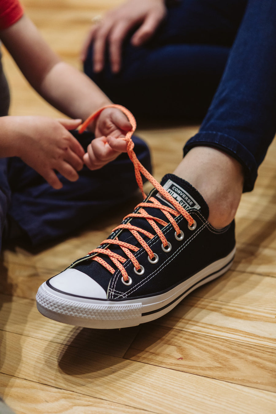 Peach & Fuchsia ticked flat shoelaces being tied on a black high-top sneaker