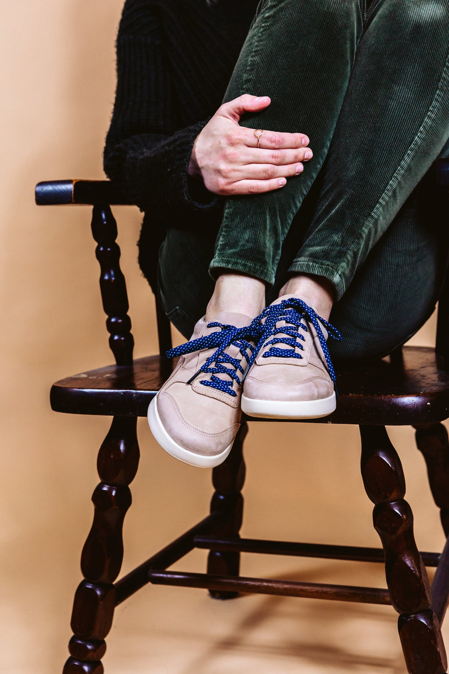 Navy & Light Blue ticked flat shoelaces worn with high-top sneakers while seated in a chair